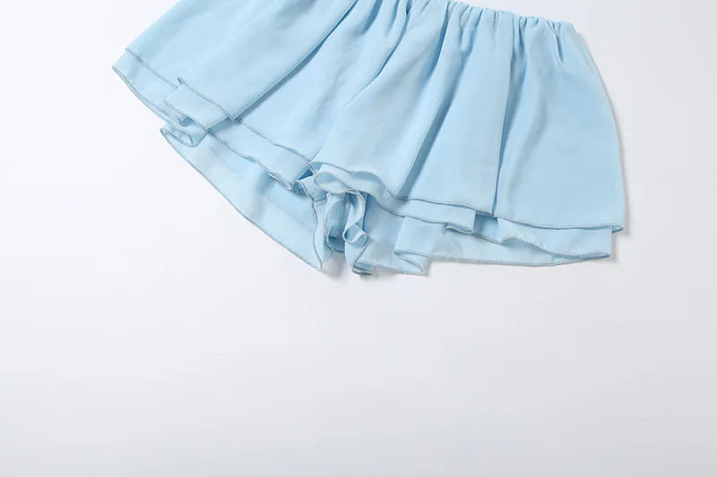 Completo coordinato due pezzi da donna sexy con scollo all'americana e volant, top corto senza schienale e minigonna pantaloncino, moda estate 2026 per vacanze